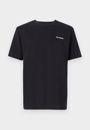 Camiseta de manga corta negra hecha de algodón, con cuello redondo y un pequeño logo blanco "SALOMON" en el área del pecho izquierdo.
