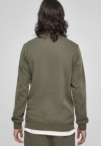 Olijfgroene sweatshirt met lange mouwen, ronde hals en ribgebreide manchetten. Zachte stof, minimalistisch ontwerp, geen zichtbare logo's of patronen.