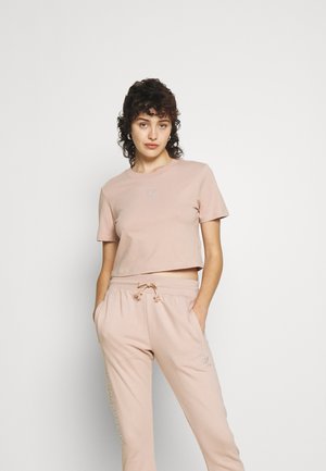 Lyserød cropped t-shirt med korte ærmer, prydet med broderet logo på brystet. Matchende joggers med snøre og sidelommer.