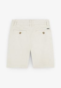 Pantaloni corti beige realizzati in morbido cotone con taglio dritto. Presentano due tasche posteriori con chiusura a bottone e un piccolo etichetta del marchio sulla vita.