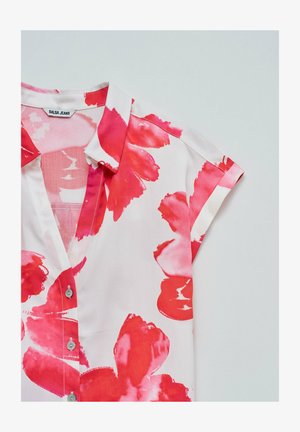Korte mouw blouse van lichtgewicht stof, met een witte basis en levendige roze bloempatronen, knoopsluiting aan de voorkant en kraagdetails.