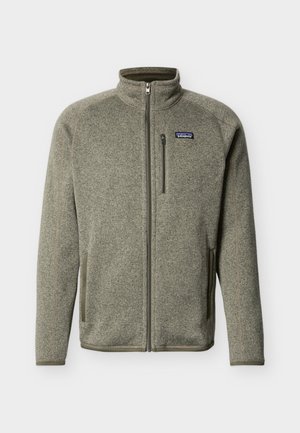 Zelena flis jakna s celotno zadrgo, stoječim ovratnikom, dvema stranskima žepoma, žepom z zadrgo na prsih in logotipom Patagonia na levi strani prsnega koša.