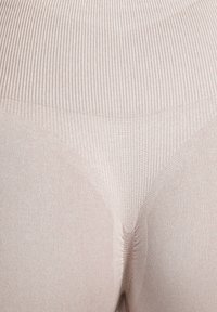 Beige naadloze legging met een geribbelde textuur, een hoge tailleband en een gladde afwerking. Heeft een nauwsluitend ontwerp en subtiele stiknaadaccenten.