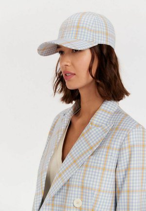 Casquette à carreaux bleus et blancs avec des accents jaunes, dotée d'une visière courbée et d'un logo brodé sur le devant, fabriquée en tissu texturé.