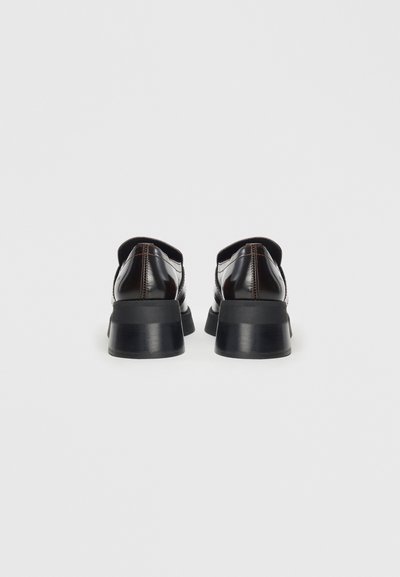 Black patent leather shoes with a chunky black heel, featuring a rounded toe and contrast stitching along the seams. Smooth texture.