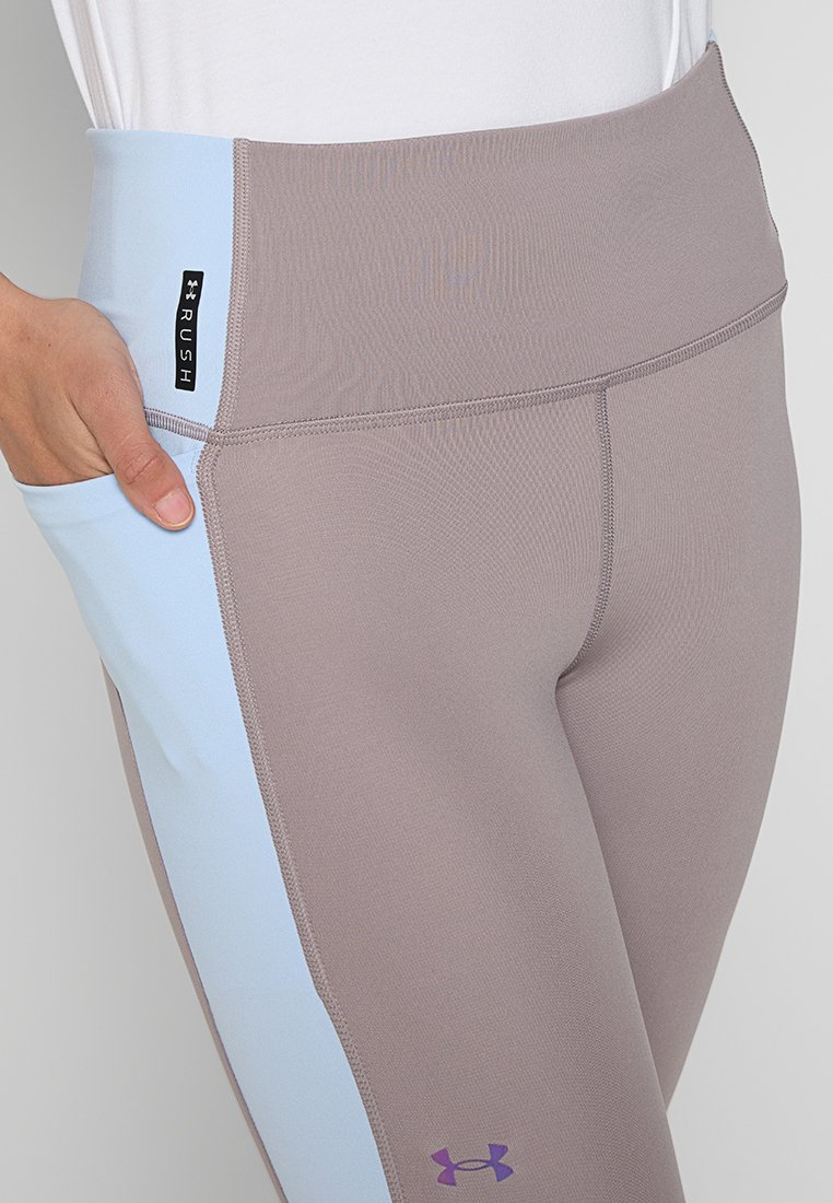 Leggings taille haute en matériau taupe texturé avec des panneaux latéraux bleu clair. Comprend une petite étiquette logo et des accents violets.