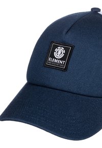 Cappellino da baseball in tessuto blu con visiera piatta. Presenta un'etichetta nera rettangolare e una superficie testurizzata.