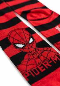 Calzini alti fino al ginocchio a strisce rosse e nere con un design di Spider-Man e testo. Realizzati in materiale morbido con una texture liscia.