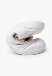 Białe składane buty wykonane z miękkiego materiału, z teksturowaną gumową podeszwą i prostym designem. Zakrzywiony kształt z minimalnymi detalami szwów.