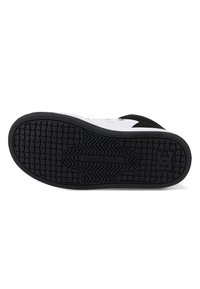 Zwarte rubberen outsole met een getextureerd grippatroon en witte tussenzool. Kenmerken zijn een zwarte suède bovenkant en een merkteken op de zool.