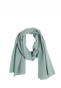 Écharpe bleu clair, faite d'un tissu texturé avec une apparence légèrement froissée. Les bords sont bruts avec de petites taches subtiles tout au long.