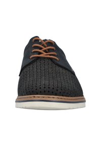 Schwarze perforierte Schuhe mit braunen Schnürsenkeln und einer hellen Sohle; die Schuhe haben ein Obermaterial aus glattem Leder und eine kontrastierend genähte Zwischensohle.