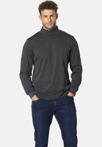 Dunkelgraues langärmliges Rollkragenhemd mit einer taillierten Passform. Weicher Textil mit gerippten Bündchen und hohem Kragen. Kombiniert mit blauen Denim-Jeans.