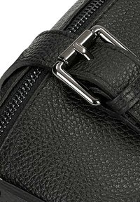 Borsa in pelle nera con finitura testurizzata, dotata di una chiusura con fibbia in argento e zip. La fibbia è posizionata su un manico.