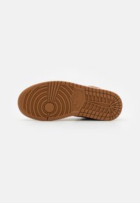 Semelle en caoutchouc marron avec des motifs de bande de roulement circulaires et linéaires, comportant un logo circulaire et des accents texturés pour une meilleure adhérence.