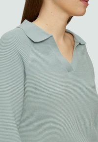 Hellblaues Pol sweater mit V-Ausschnitt, das eine gerippte Textur und einen lässigen Schnitt aufweist. Der Kragen hat ein weich gerundetes Design.