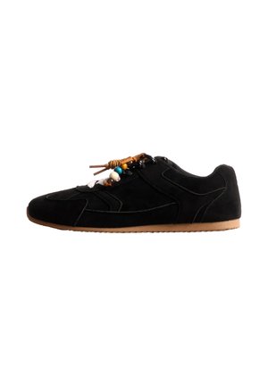 Basket basse noire en daim, ornée de perles multicolores décoratives sur les lacets et dotée d’une semelle en caoutchouc beige, présentée de profil sur fond blanc.
