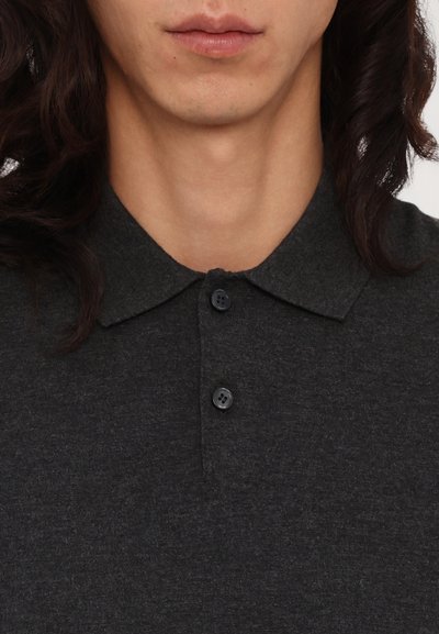 Tmavošedá pólová košela s klasickým golierom, dvoma čiernymi gombíkmi a textúrovanou tkaninou. Detailný pohľad na výstrih.