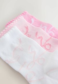 Tre paia di calzini: uno bianco, due tonalità di rosa. Cuffie costinate con una morbida texture. Ogni calzino presenta un motivo stampato di un rosa chiaro.