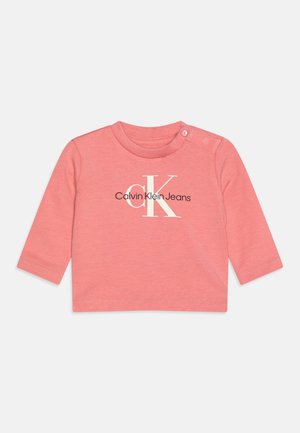 T-shirt bébé à manches longues rose avec logo Calvin Klein Jeans et deux boutons-pression sur l’épaule gauche.