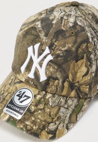 Καπέλο μπέιζμπολ με καμουφλάζ σχέδιο σε γήινους τόνους, με λευκό κεντημένο λογότυπο New York Yankees και ρυθμιζόμενο λουράκι.