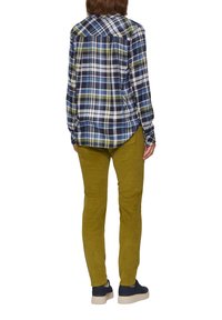 Kariertes Hemd in Marineblau, Grün und Weiß; grüne Cord-Hose; marineblaue Schuhe mit heller Sohle. Ansicht von hinten.