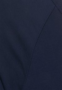 Mörkblått tyg med en jämn textur och diagonala sömmar. Materialet verkar stretchigt och är lämpligt för figurnära kläder.