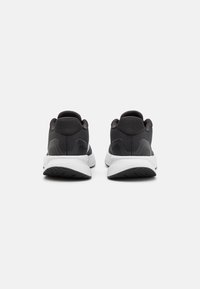 Černé sportovní boty s horní částí z texturované síťoviny, polstrovaným límcem a kontrastní bílou stélkou. Mají gumovou podrážku s protišmykovým vzorem.