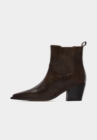 Σκούρο καφέ δερμάτινο μποτάκι αστραγάλου με μυτερή μύτη, τακούνι block και λουράκι έλξης στο πίσω μέρος, απεικονιζόμενο προφίλ σε λευκό φόντο.