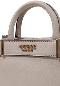 Borsa sintetica beige con superficie testurizzata, manici arrotondati e dettagli in metallo dorato con logo "GUESS EST.1981".