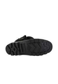 Suola di scarpa in gomma nera con motivo testurizzato, caratterizzata da scanalature profonde e impugnature circolari per trazione e stabilità.