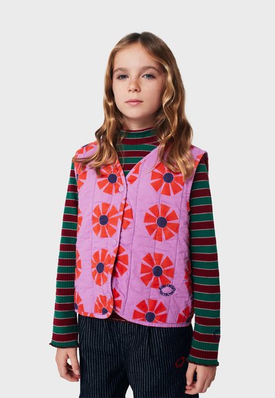 Gilet trapuntato di colore viola chiaro con un motivo floreale rosso e nero; presenta bottoni rotondi e una vestibilità leggermente ampia su una maglietta a maniche lunghe a righe.