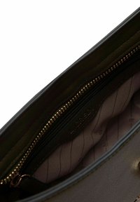 Leer handtas interieur met een donkergroene afwerking, voorzien van een gouden rits en een lichtpaarse gevoerde binnenkant met patroon. Inclusief een klein ritsvakje.