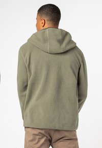 Olijfgroene fleece pullover met een capuchon, met een gestructureerd oppervlak. De achterkant laat een ontspannen pasvorm en een eenvoudig ontwerp zien.