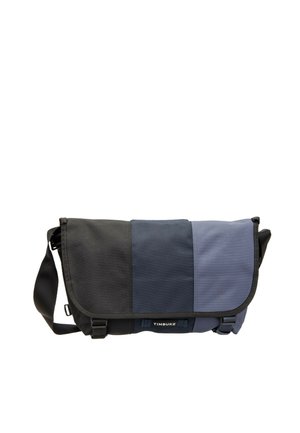 Messenger bag with black and two shades of blue panels, adjustable shoulder strap, and front buckles, branded Timbuk2.