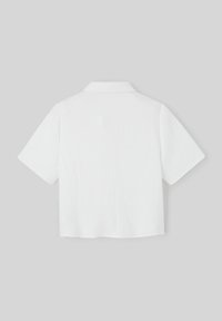 Chemise blanche à manches courtes avec un tissu texturé, un col et un design ample. L'arrière présente un ourlet droit et des détails subtils.