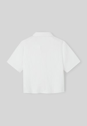 Chemise blanche à manches courtes avec un tissu texturé, un col et un design ample. L'arrière présente un ourlet droit et des détails subtils.