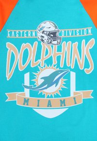 Turkos T-shirt med orange raglanärmar, prydd med ett grafiskt tryck av en fotbollshjälm, delfinlogotyp och texten "DOLPHINS MIAMI".