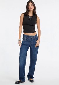 Musta lyhyt toppi, siniset leveälahkeiset farkut ja mustat ballerinat. Farkuissa on klassinen malli, jossa on etutaskut ja rento istuvuus.