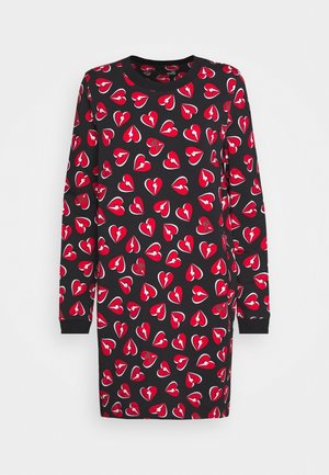 Zwarte jurk met lange mouwen met patroon van een rood gebroken hart en een witte bliksemschicht, voorzien van een ronde halslijn en geribbelde manchetten.