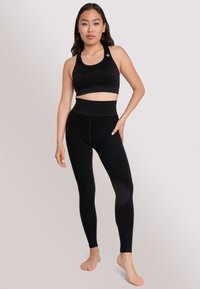 Set di reggiseno sportivo e leggings neri. Il reggiseno presenta un scollo rotondo, mentre i leggings hanno un elastico in vita alto e un tessuto liscio e morbido.