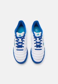 Bílé sportovní boty s modrými tkaničkami a akcenty. Mají texturovaný svršek a plochou gumovou podrážku s dezénem. Logo na jazyku.