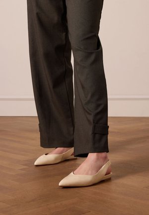 Beige slingback schoenen met een puntige neus, een gladde leren textuur en een lage hak, gecombineerd met donkergrijze tapered broek.