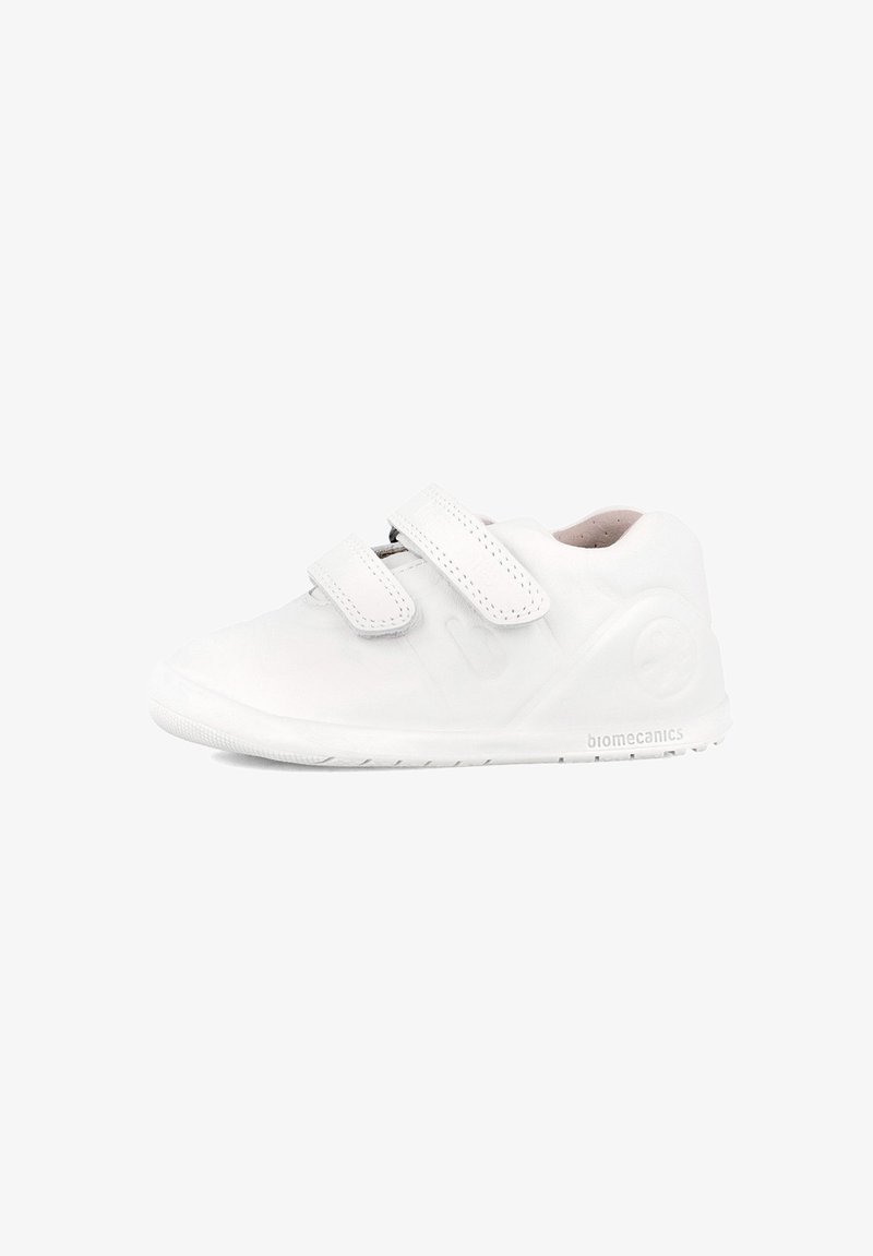 Zapatilla blanca con un acabado suave y mate, que presenta dos correas ajustables de Velcro y una suela de goma texturizada. Logo de la marca en el lado.