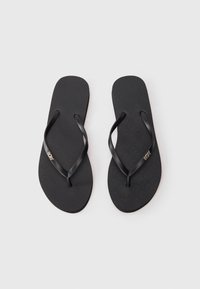Schwarze Flip-Flops mit strukturierten Sohlen und dünnen Riemen. Besitzen ein kleines goldenes Logo auf einem Riemen. Einfaches Design und leichtes Material.