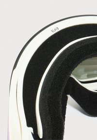 Primo piano dell'imbottitura in schiuma nera e della montatura bianca degli occhiali con marchio "EA7" sul bordo superiore.