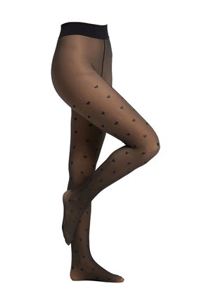 Benen in zwarte doorschijnende panty’s met kleine zwarte hartjespatronen, met één voet plat en de andere achter de knie opgetrokken.