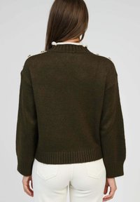 Pull en mailles vert foncé avec un ourlet et des poignets côtelés. Présente des boutons dorés décoratifs sur l'épaule et une bordure de col blanche.