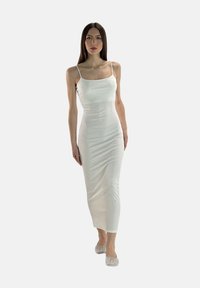 Robe maxi blanche ajustée avec fines bretelles, en tissu lisse ; dotée d'un décolleté droit et d'un ourlet à la cheville.
