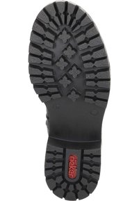 Semelle de chaussure en caoutchouc noir présentant un motif de texture avec des formes en diamant et des lignes, marqué par un logo rouge "Rieker".